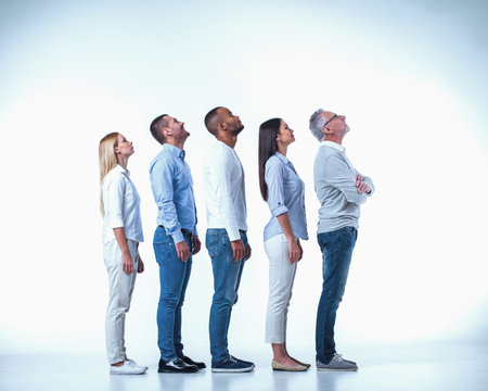 Side view of beautiful business people in smart casual wear looking upward and smiling while standing one by one on a white backgroundの写真素材