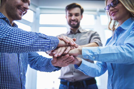 Beautiful business team are holding hands together and smiling while working in office