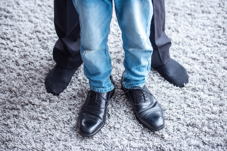 Cropped image of father and son spending time together. Little boy is in dad's shoes