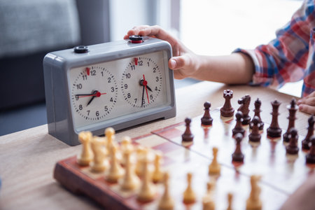 Cropped image of little boy playing chess, hand on timerの写真素材