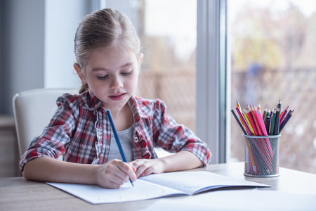 Cute little girl is drawing and smiling while spending time at homeの写真素材