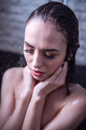 Beautiful naked young woman is taking shower in bathroom