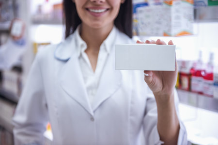 Cropped image of beautiful female pharmacist holding a medication and smiling while standing in pharmacyの写真素材