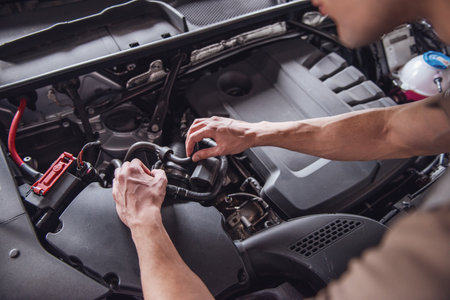 Cropped image of handsome young auto mechanic in uniform repairing car in auto serviceの写真素材