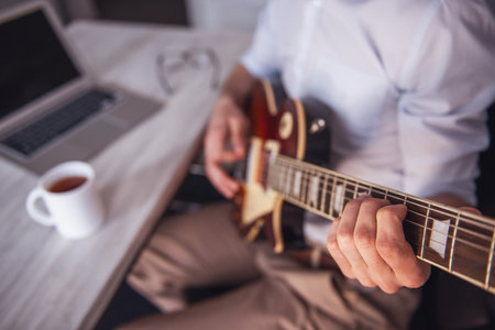 Cropped image of young businessman playing guitar in his office during the breakの写真素材