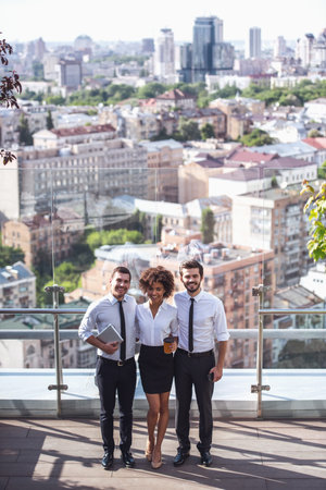 Full length portrait of beautiful business people looking at camera and smiling while standing on...