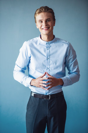 Handsome young businessman in suit is looking at camera and smiling, on gray backgroundの写真素材