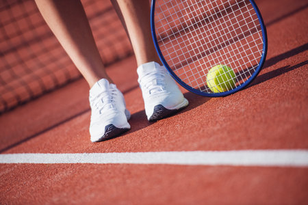 Cropped image of girl holding tennis racket while playing tennis on court outdoorsの写真素材
