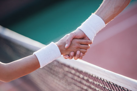 Cropped image of man and woman shaking their hands while playing tennis on tennis court outdoorsの写真素材