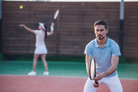Beautiful young couple are playing tennis as a team on tennis court outdoorsの写真素材