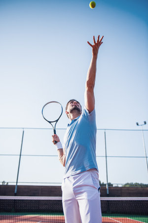 Handsome man is playing tennis on tennis court outdoorsの写真素材