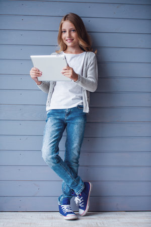 Pretty teenage girl is using a digital tablet and smiling whileの写真素材
