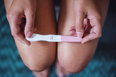 Cropped image of woman holding a pregnancy test on her kneesの写真素材