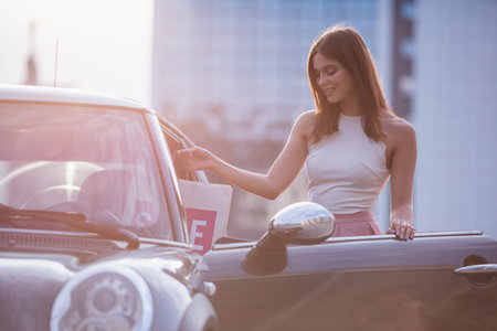 Beautiful elegant brunette girl is getting into her car and smilingの写真素材