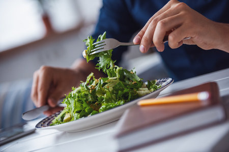 Cropped image of young man eating salad in the cafeの写真素材