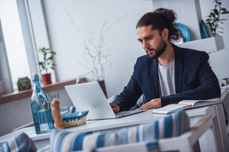 Handsome young businessman with long dark hair is working with a laptop in a cafeの写真素材