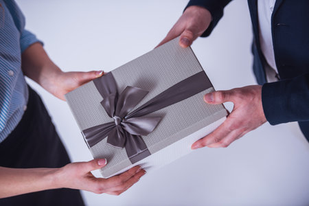 Cropped image of couple in office clothes holding a gift box, isolated on whiteの写真素材