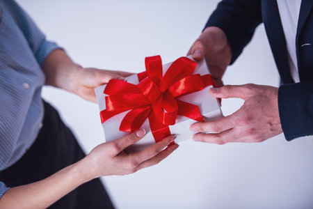 Cropped image of couple in office clothes holding a gift box, isolated on whiteの写真素材