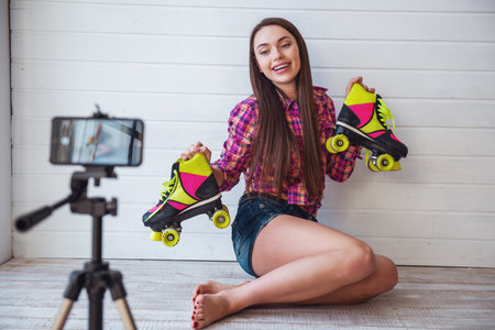 Portrait of young beautiful girl blogger with long hair with rollers in hands on gray background makes shooting for blogの写真素材