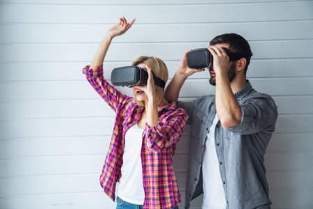 Cheerful couple looking into virtual boxes and emotions gesturing handsの写真素材