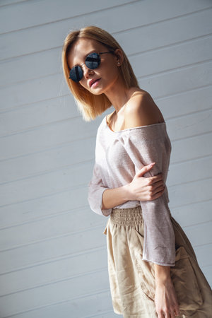 Portrait of young beautiful girl standing in sunglasses and smiling at camera at homeの写真素材