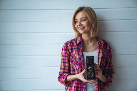 Young emotional girl while shooting with old camera on light backgroundの写真素材