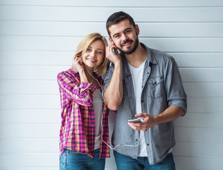 Portrait of young cheerful loving couple smiling looking at camera and hugging each other on light backgroundの写真素材