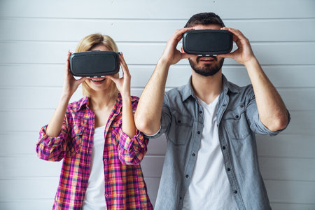 Cheerful couple looking into virtual boxes and emotions gesturing handsの写真素材