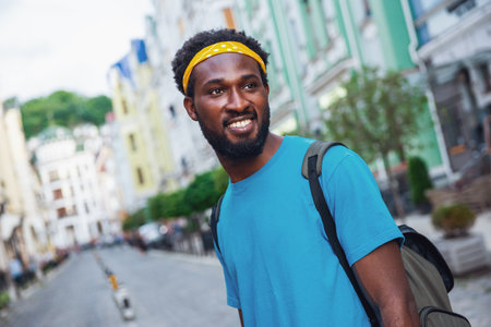 A young man laughs while walking the streets of the bridge with a backpackの写真素材
