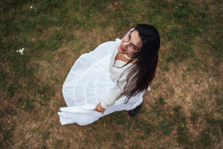 Retro style. Young beautiful girl with black chic hair in a white dress is looking at the camera, top view.の写真素材