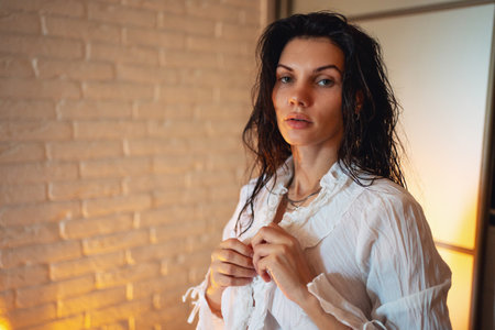 Portrait of a young beautiful sexy girl with black chic hair getting dressed at home in the bedroom.の写真素材