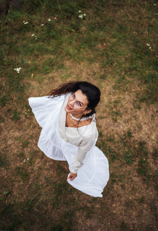 Retro style. Young beautiful girl with black chic hair in a white dress is looking at the camera, top view.の写真素材