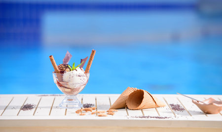 Glass with mint ice cream scoops on blur bokeh background with copy space. Waffle cones on white...