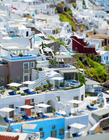Top view from above of Santorini villas. Panorama of small houses with blue water swimming pool on white terrace, blur backgroundの写真素材