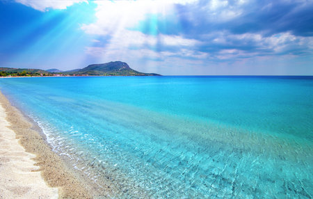 Blue sky, white clouds, sun rays, clear sea water background. Toroni beach, Sitonia, Greece