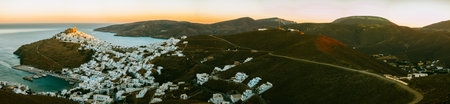 A wide panoramic view of Astypalaia Chora with the sun setting and a small spot of light remaining on top of the fortressの写真素材