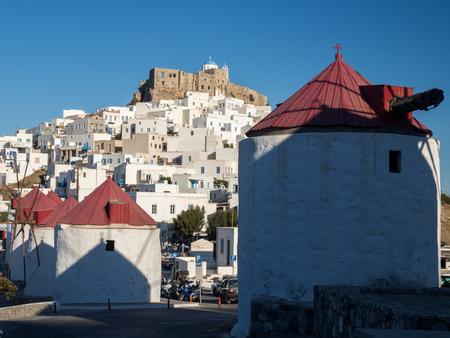 The traditional white windmills with the red roofs and the fortress of Astypalaia in the backの写真素材