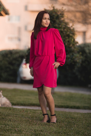 Young brunette woman in pose outdoors with elegant short dress and smiling.の写真素材