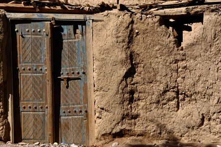 Old peeled blue door on a willage mud house in Omanの写真素材