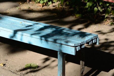 Blue painted bench in a park in a run down conditionの写真素材