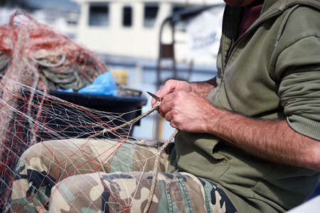 hands at work on fishing netの写真素材