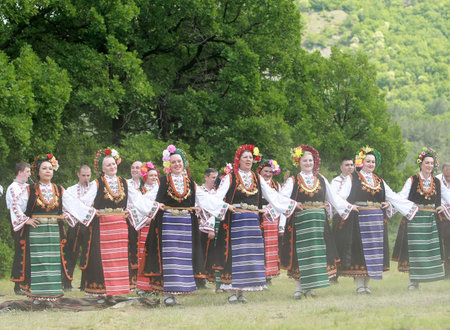 Varvara, Bulgaria - May 5, 2015: People in traditional costumes dance bulgarian horo a meadow near...