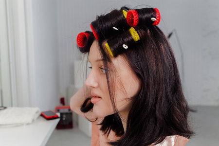 Portrait of a young woman in a light robe with hair rollers.の写真素材