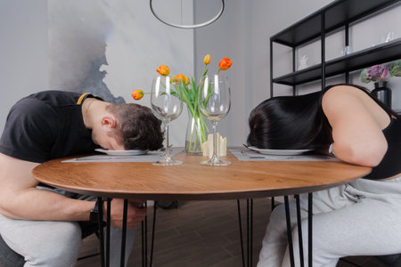 A man and a woman sits in front of an empty plate holding his head and starving. Hunger, Food Insecurity, inability to cook concept.の写真素材