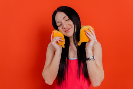 Close-up portrait of a charming girl enjoying the comfort of a travel pillow against a bright red isolated background.の写真素材