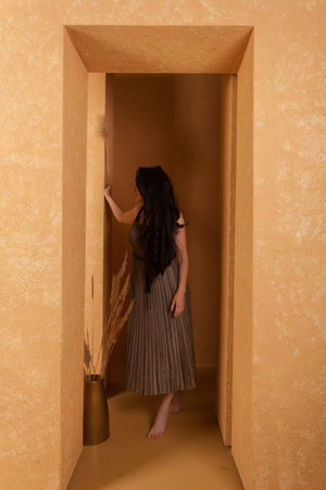 A woman wearing dress in a beige sandstone room. warm and cozy atmosphere.の写真素材