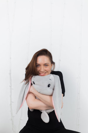 A girl is playing with a toy plush rabbit in a minimalist bright room. childhood innocence and playfulness concept.の写真素材