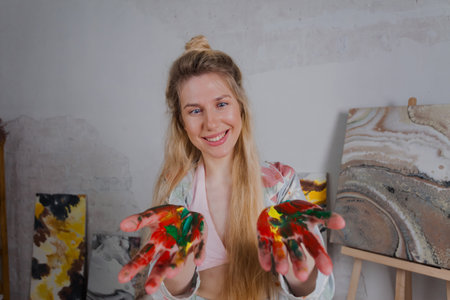 Talented Female Artist smiling happy showing colorful painted hands. Colorful, Emotional, Sensual Painter Creating Abstract Modern Art. Creative Expression concept.の写真素材