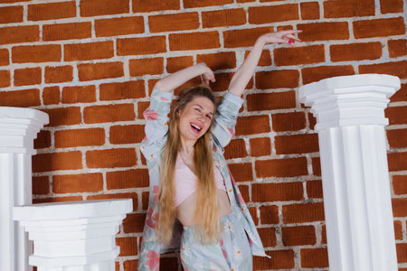 Talented Female Artist smiling, stands between marble columns. Colorful, Emotional, Sensual Artist Creating Abstract Modern Art. Creative Expression concept. Brick wall background.の写真素材