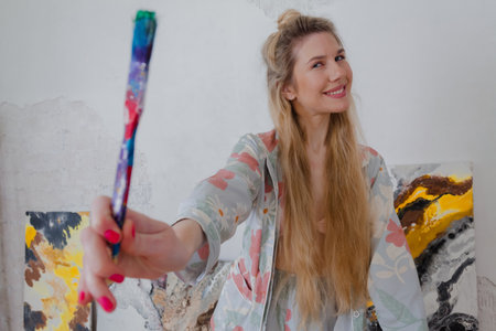 Talented happy Female Artist smiling and holding a brush. Colorful, Emotional, Sensual Painter Creating Abstract Modern Art. Creative Expression concept.の写真素材